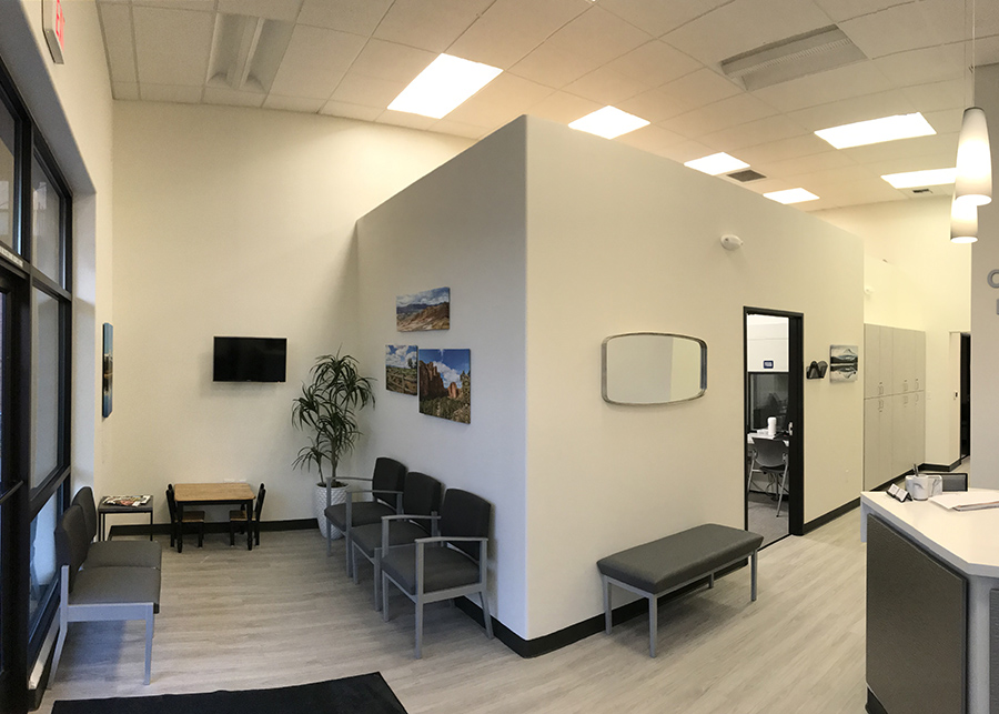 A wide-angle view of the waiting area and hall, grey laminate flooring, light-colored walls with photos of local landmarks